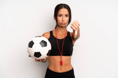 Latin kökenli güzel bir kadın kızmış, baş parmağını kaldırmış. futbol ve fitness konsepti