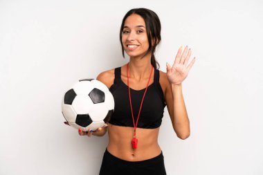 İspanyol güzel kadın mutlu bir şekilde gülümsüyor, el sallıyor, seni selamlıyor ve selamlıyor. futbol ve fitness konsepti