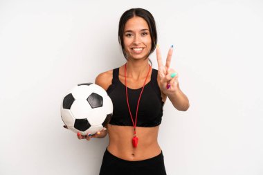 İspanyol güzel kadın gülümsüyor ve arkadaş canlısı görünüyor, ikinciyi gösteriyor. futbol ve fitness konsepti