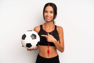 İspanyol güzel kadın neşeyle gülümsüyor, mutlu hissediyor ve bir tarafı işaret ediyor. futbol ve fitness konsepti