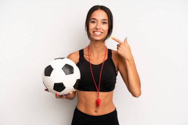 Hispanik güzel kadın kendi gülüşünü işaret ederek kendine güvenerek gülümsüyor. futbol ve fitness konsepti