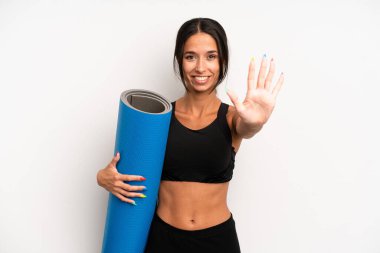 İspanyol güzel kadın gülümsüyor ve arkadaş canlısı görünüyor, beş numarayı gösteriyor. fitness ve yoga konsepti