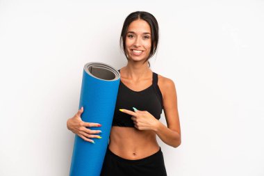 İspanyol güzel kadın neşeyle gülümsüyor, mutlu hissediyor ve bir tarafı işaret ediyor. fitness ve yoga konsepti