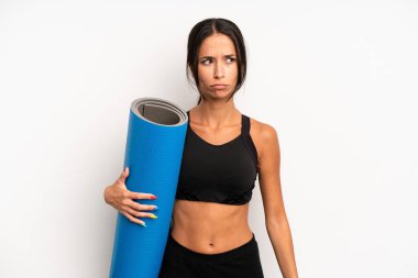 Hispanik güzel kadın üzgün, üzgün ya da kızgın hissediyor ve yana bakıyor. fitness ve yoga konsepti