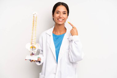 Hispanik güzel kadın kendi gülüşünü işaret ederek kendine güvenerek gülümsüyor. hekim öğrenci konsepti