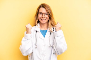 pretty blonde young woman feeling shocked,laughing and celebrating success. physician or doctor student concept