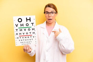 pretty blonde young woman feeling happy and pointing to self with an excited. optical vision test concept