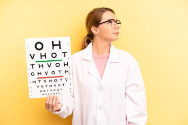 pretty blonde young woman on profile view thinking, imagining or daydreaming. optical vision test concept