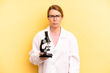 pretty blonde young woman feeling sad and whiney with an unhappy look and crying. scients student with a microscope concept