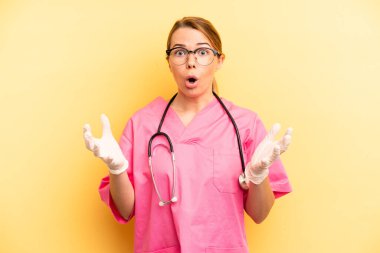pretty blonde young woman feeling extremely shocked and surprised. veterinarian student concept