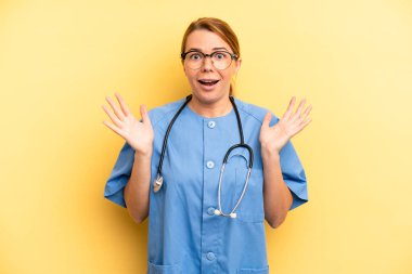 pretty blonde young woman feeling happy and astonished at something unbelievable. physician or doctor student concept