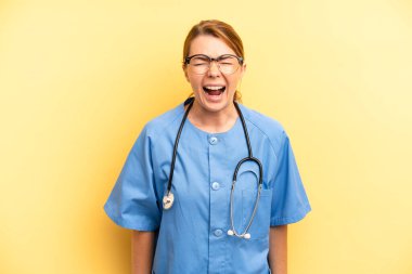 pretty blonde young woman shouting aggressively, looking very angry. physician or doctor student concept