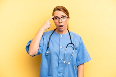 pretty blonde young woman looking surprised, realizing a new thought, idea or concept. physician or doctor student concept