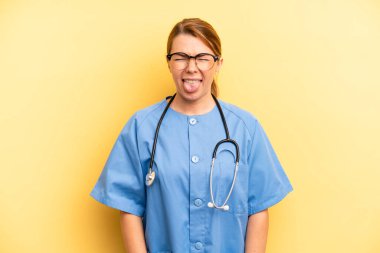 pretty blonde young woman feeling disgusted and irritated and tongue out. physician or doctor student concept