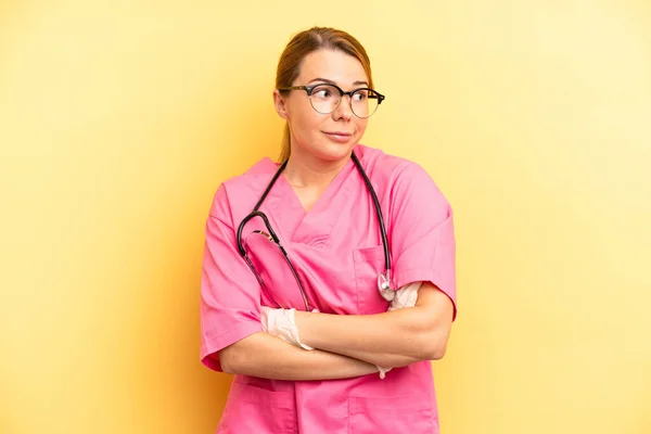 pretty blonde young woman shrugging, feeling confused and uncertain. veterinarian student concept