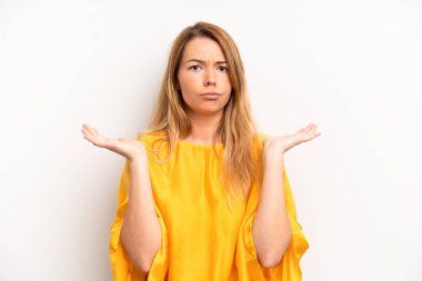 Sarışın, güzel bir kadın şaşkın ve şaşkın hissediyor, şüpheci, farklı seçenekleri tartıyor veya komik bir ifadeyle seçiyor.