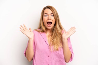 Sarışın, güzel bir kadın mutlu ve heyecanlı görünüyor. Beklenmedik bir sürprizle şoke olmuş. İki eli yüzü açık.