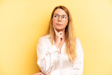 Sarışın, güzel bir kadın mutlu bir şekilde gülümsüyor ve hayal kuruyor ya da şüphe ediyor.