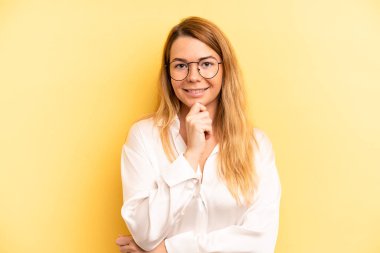 Güzel sarışın kadın mutlu görünüyor ve gülümsüyor. El pençe divan, merak ediyor ya da soru soruyor. Seçenekleri karşılaştırıyor.