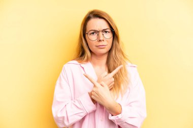 Şaşkın ve şaşkın görünen sarışın güzel kadın, güvensiz ve şüpheyle zıt yönleri işaret ediyor.