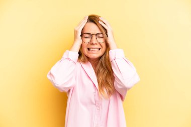 sarışın güzel bir kadın stresli ve endişeli, depresyonda ve hayal kırıklığına uğramış, iki elini de başa kaldırıyor.