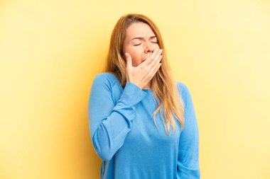 Sarışın, güzel bir kadın sabahın erken saatlerinde uykulu, yorgun ve sıkkın bir şekilde esniyor.