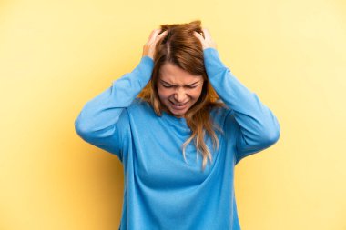 Sarışın, güzel bir kadın stresli ve hayal kırıklığına uğramış hissediyor, ellerinizi havaya kaldırıyor, yorgun, mutsuz ve migren ağrısı çekiyor.