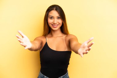 Asyalı güzel kadın neşeyle gülümsüyor sıcak, dostça, sevgi dolu bir kucaklama veriyor, mutlu ve sevimli hissediyor.