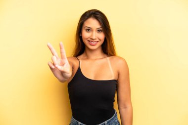 Asyalı güzel kadın gülümsüyor ve arkadaş canlısı görünüyor. İki ya da iki numarayı gösteriyor. Elleri önde, geriye doğru sayıyor.