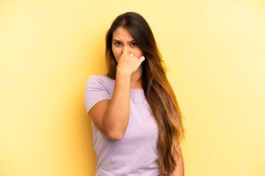 Asyalı güzel kadın iğreniyor, kötü ve nahoş bir koku duymamak için burnunu tutuyor.