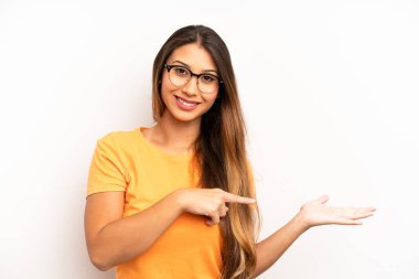 Asyalı güzel kadın gülümsüyor, mutlu, kaygısız ve tatmin olmuş hissediyor, fotokopi alanındaki konsepte ya da fikre işaret ediyor.