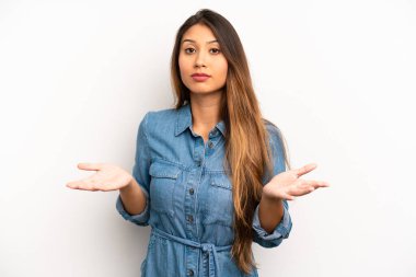 Asyalı güzel kadın şaşkın ve şaşkın hissediyor, doğru cevap veya karardan emin değil, bir seçim yapmaya çalışıyor.