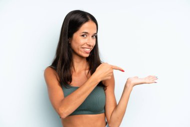 İspanyol güzel kadın gülümsüyor, mutlu, kaygısız ve tatmin olmuş hissediyor, fotokopi alanındaki konsepte ya da fikre işaret ediyor.