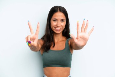 İspanyol güzel kadın gülümsüyor ve arkadaş canlısı görünüyor, 7 ya da 7 numarayı gösteriyor, eli önde, geriye doğru sayıyor.