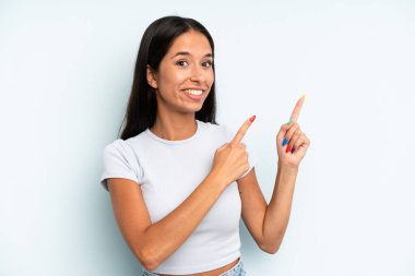 İspanyol güzel kadın mutlu bir şekilde gülümsüyor ve her iki elinle de fotokopi alanında nesne gösteriyor.