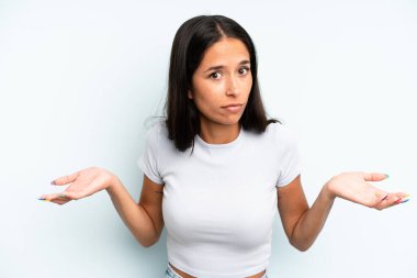 hispanic pretty woman feeling clueless and confused, having no idea, absolutely puzzled with a dumb or foolish look