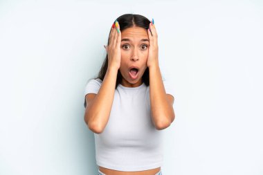 İspanyol güzel kadın hoş olmayan bir şekilde şok olmuş, korkmuş ya da endişeli görünüyor, ağzı sonuna kadar açık ve iki kulağını da elleriyle kapatıyor.