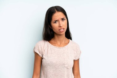 hispanic pretty woman feeling puzzled and confused, with a dumb, stunned expression looking at something unexpected