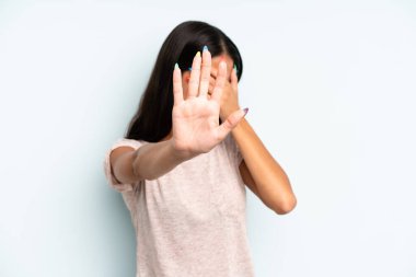 İspanyol asıllı güzel bir kadın elleriyle yüzünü örtüyor ve diğer elini kamerayı durdurmak için öne koyuyor, fotoğraf ya da resimleri reddediyor.