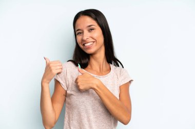 İspanyol güzel kadın neşeyle gülümsüyor ve yan taraftaki fotokopi alanını gösteriyor, mutlu ve tatmin olmuş hissediyor.