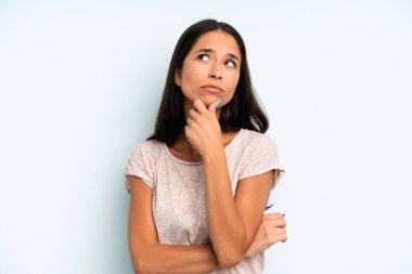 Hispanik güzel kadın düşünceli, meraklı ya da hayal kuruyor, hayal kuruyor ve uzayı kopyalamak için yukarı bakıyor.