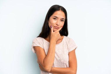 İspanyol güzel kadın ciddi, düşünceli ve güvensiz görünüyor, bir kolu çapraz ve çene üzerinde, seçenekleri tartıyor