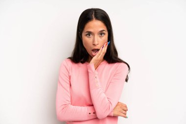 İspanyol güzel kadın şok ve inançsızlık içinde ağzı açık, elleri yanağında ve kolları çaprazlanmış, sersemlemiş ve şaşırmış hissediyor