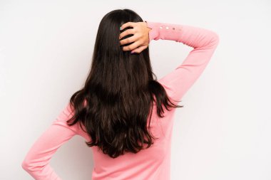 Hispanik güzel kadın düşünüyor ya da şüphe ediyor, kafasını kaşıyor, şaşkın ve şaşkın hissediyor, arkaya ya da arkaya bakıyor.