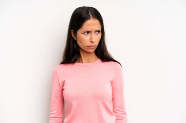 Hispanik güzel kadın üzgün, üzgün ya da kızgın hissediyor ve olumsuz bir tutumla yan yana bakıyor, anlaşmazlık içinde kaşlarını çatıyor
