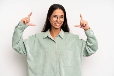 İspanyol asıllı güzel bir kadın iki eliyle kendi gülüşünü çiziyor, olumlu ve mutlu görünüyor, sağIık kavramı.