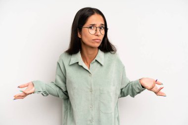 hispanic pretty woman feeling clueless and confused, having no idea, absolutely puzzled with a dumb or foolish look