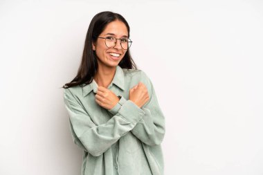 İspanyol güzel kadın neşeli bir şekilde gülümsüyor ve kutluyor, yumruklarını sıkıp kollarını kavuşturuyor, mutlu ve pozitif hissediyor.