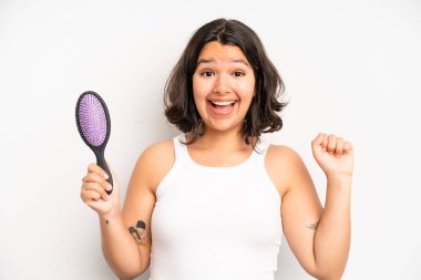 hispanic pretty girl smiling happily with friendly and  offering and showing a concept. hair comb concept