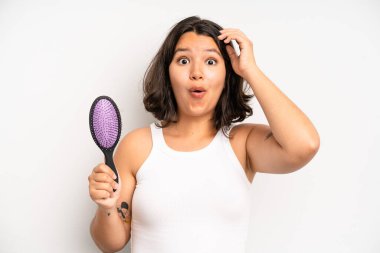 hispanic pretty girl smiling proudly and confidently making number one. hair comb concept